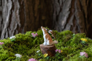 This photo shows an early assemblage piece made by artist Holly Nelson, age 10. It includes a tiny bone china fox, sitting on a miniature tree stump on a bed of moss.