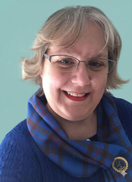 A photo of Holly Nelson in her Elliot clan tartan and a bright blue sweater.